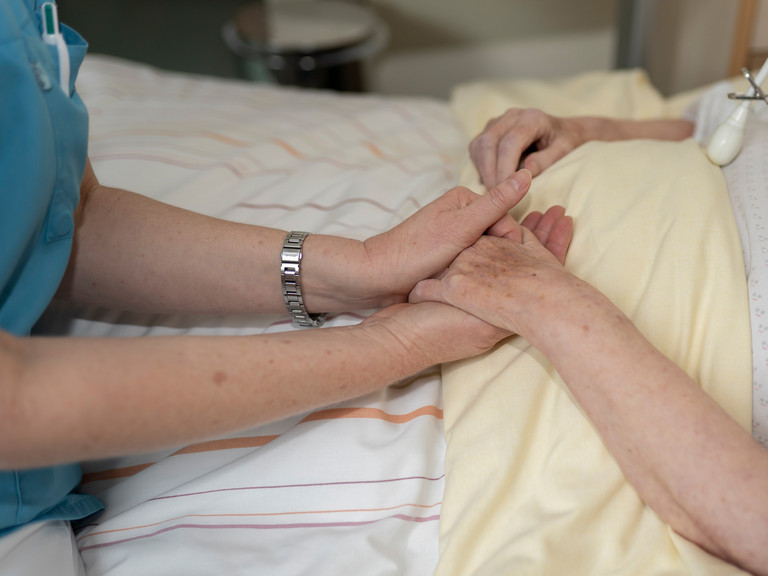 Pflegekraft hält Hand von Hospizgast - Würdiges Sterben im Diakonie Hospiz Wannsee